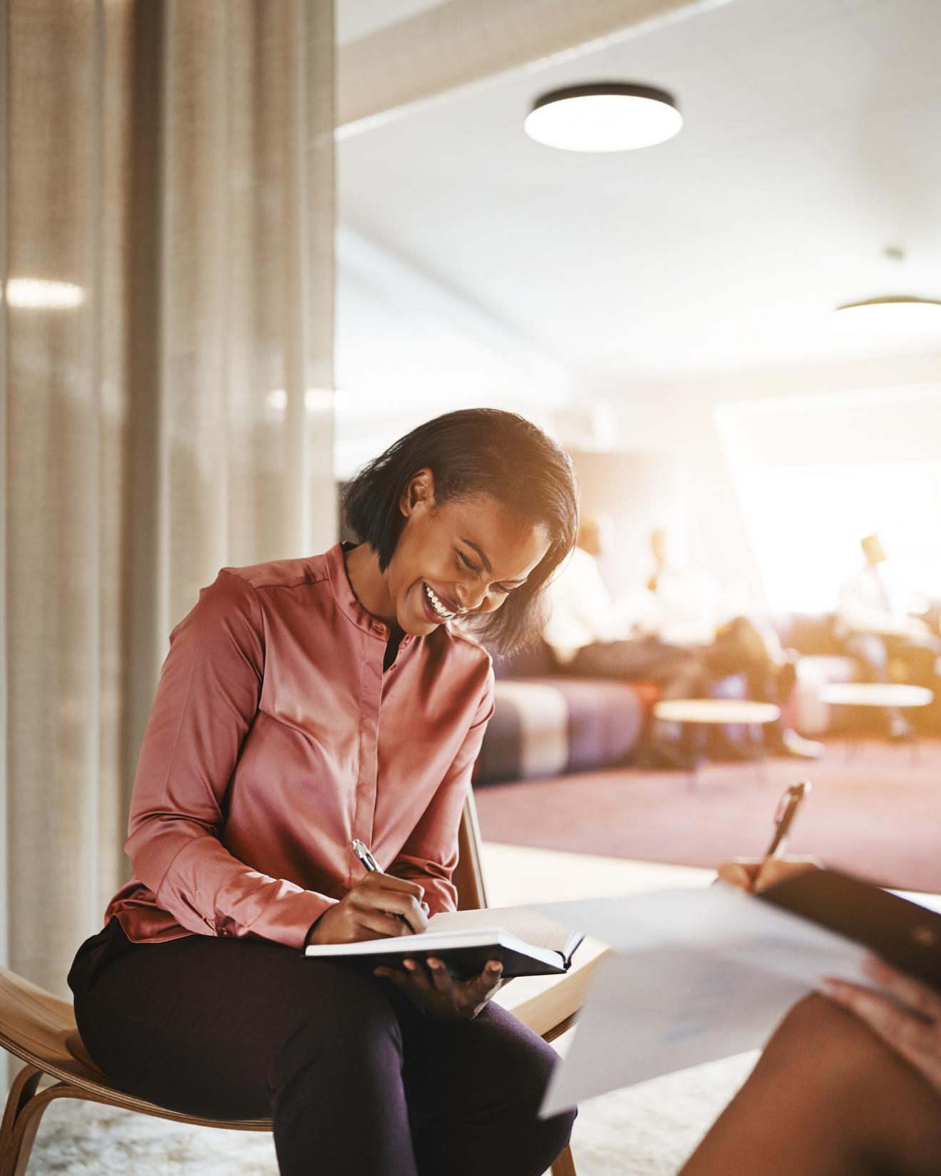 A person laughing with a colleague as they go over papers in an office together