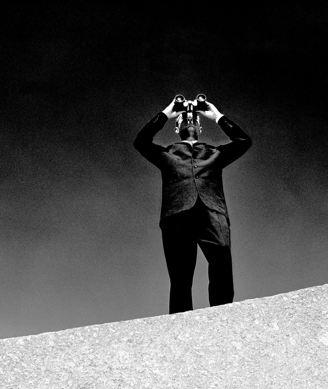 Man in suit looking through binoculars