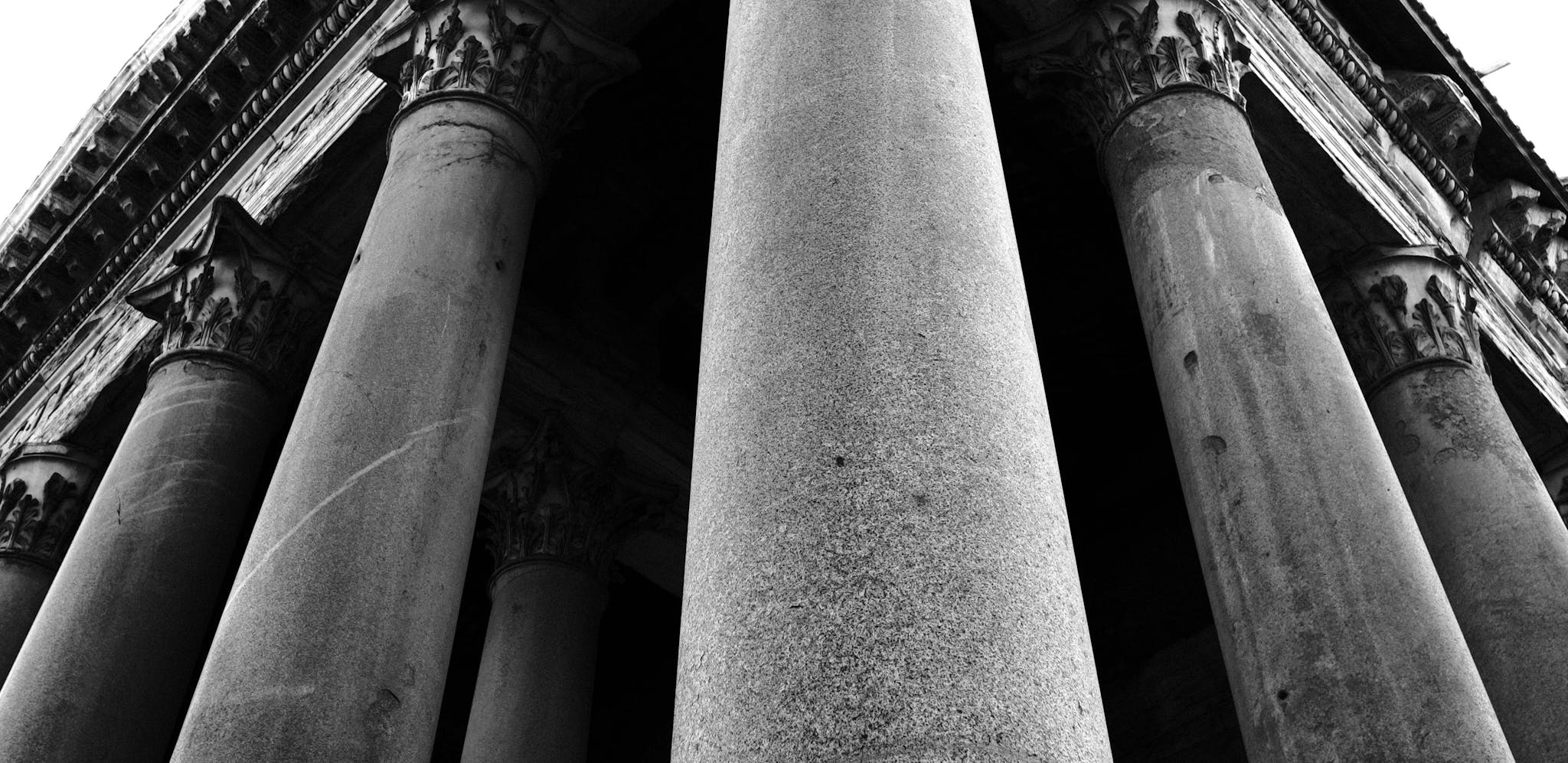 Black and white image taken looking up at the stone columns of a classical building