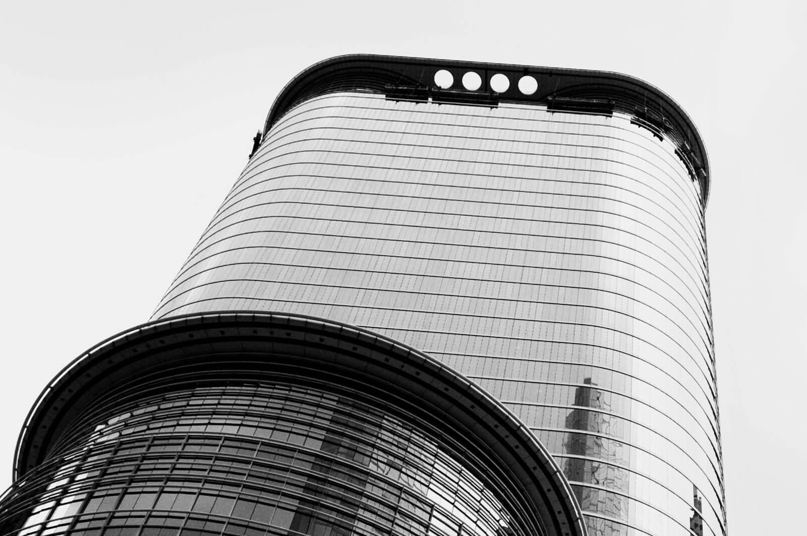 A photo from the ground level upwards to sky scrapers showing reflections of other lage buildings