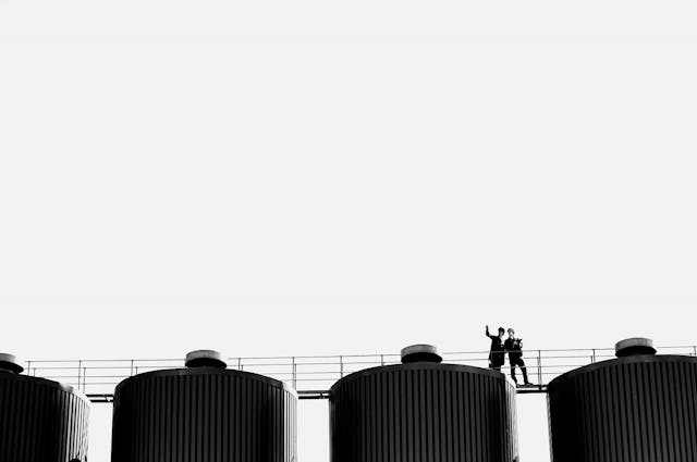 People walking on a gangway over large storage vats