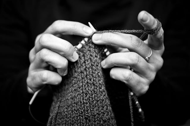 Human hand knitting woolen with needle.