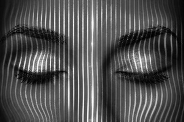 feminine face with many parallel vertical lines of light shining on its surface