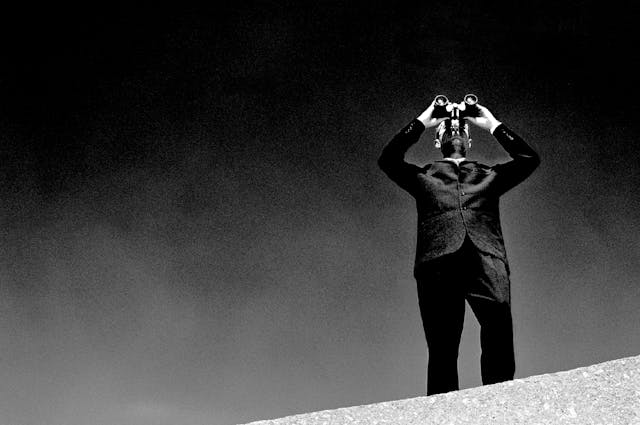 A man standing on a rock looking through binoculars
