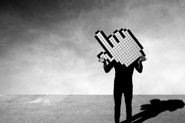 A man holding a big mouse pointer on empty concrete floor.